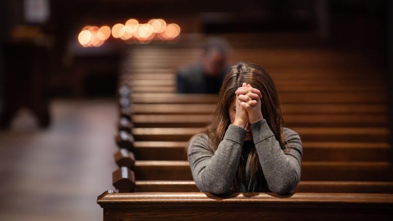 A person prays in a pew in Trinity Church