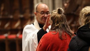 Father Phil Jackson imposes ashes on a parishioner on Ash Wednesday in Trinity Church