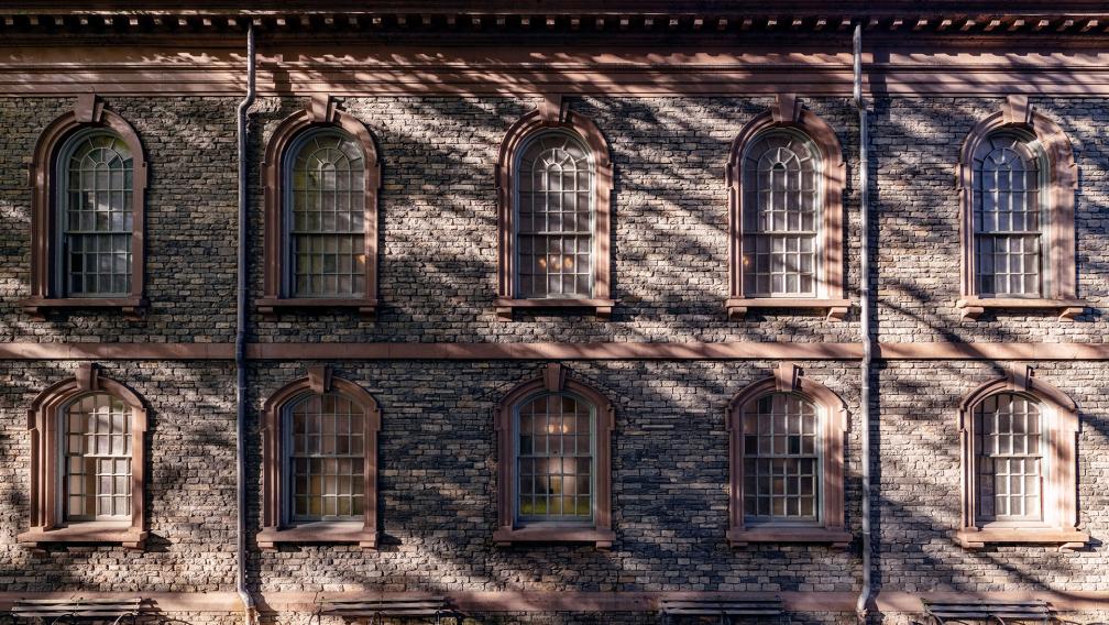 An exterior wall of St. Paul's Chapel covered in the shadow of a tree