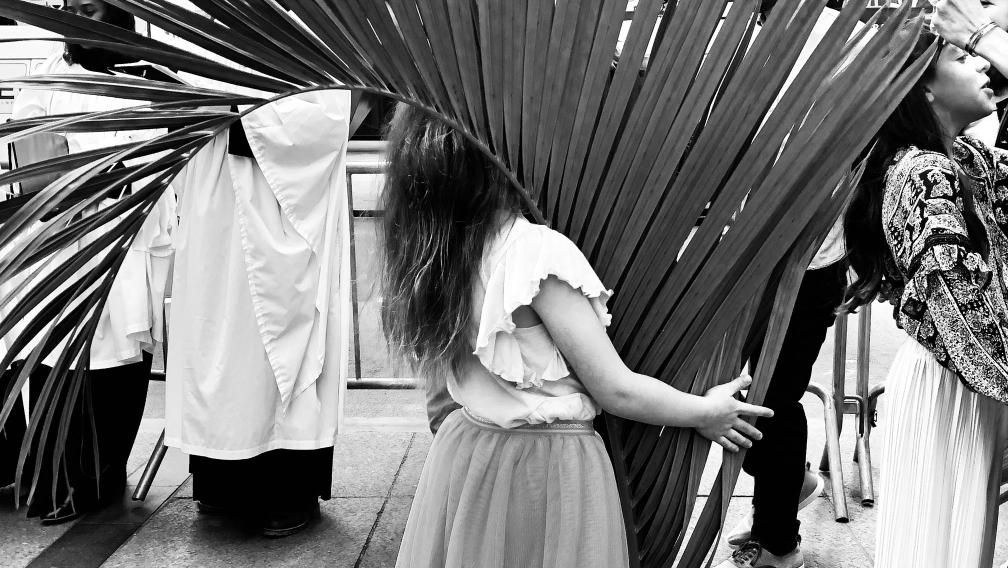 A child carries a large palm branch in a black and white photograph