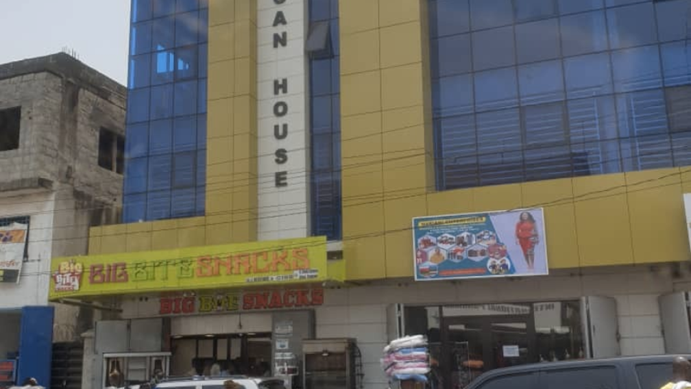 Exterior shot of the Anglican House structure in Freetown, Sierra Leone. People stand outside the building in the foreground.