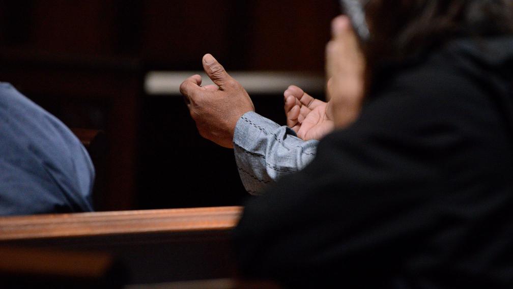 A person lifts up their hands in prayer in Trinity Church