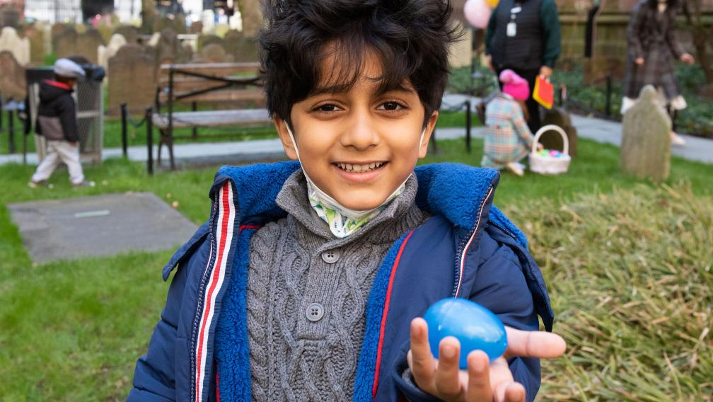 A child finds an Easter egg in Trinity Churchyard on Easter Day