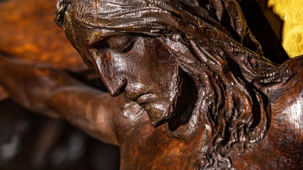 A close-up photo of a wood carving of Jesus on the cross