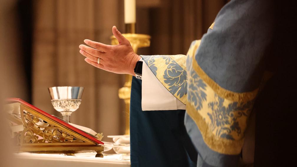 A hand stretched out over the table during Holy Eucharist at Trinity Church
