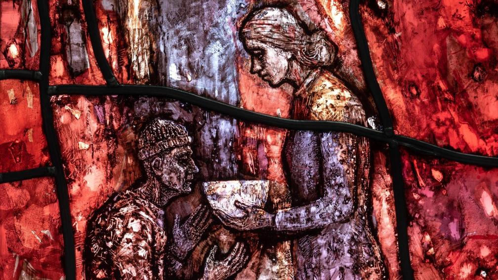 Stained-glass window closeup of woman feeding a person in need.