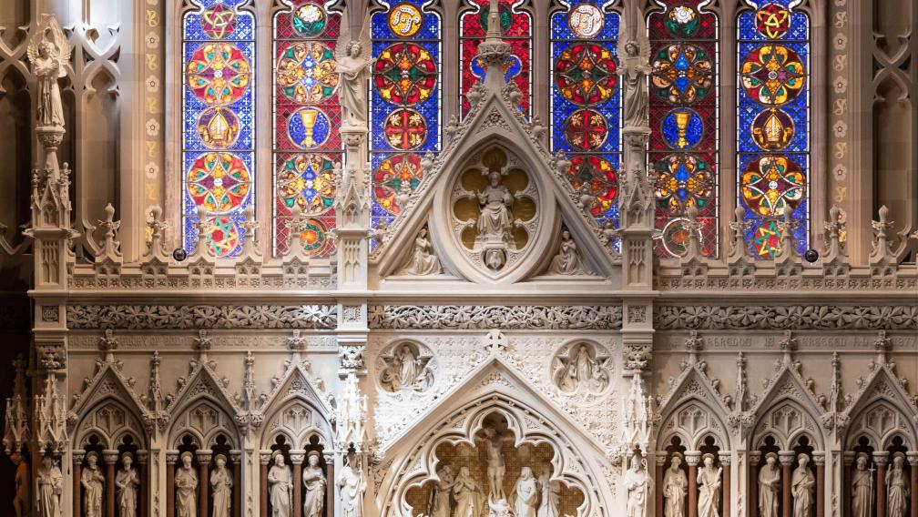 A beam of light streams across the stained glass and reredos in Trinity Church