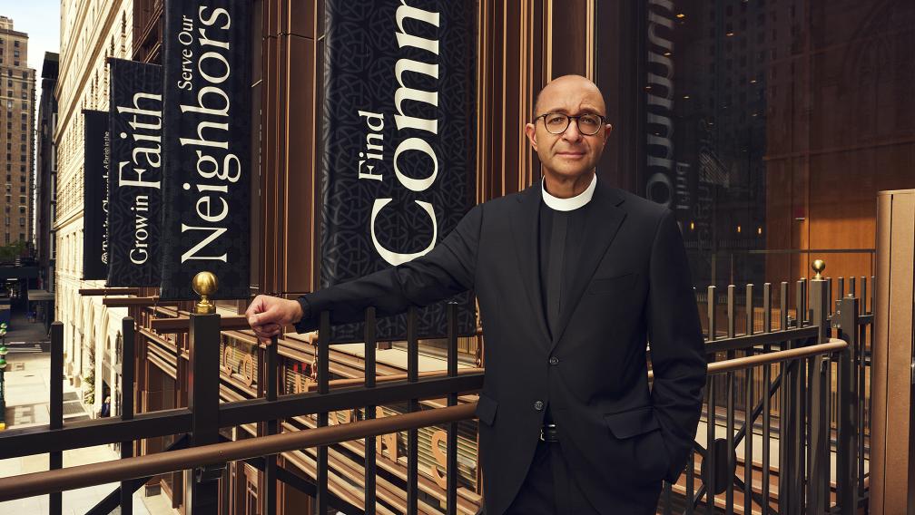 The Rev. Phil Jackson, Trinity’s rector, stands on a pedestrian bridge in front of Trinity Commons in Lower Manhattan