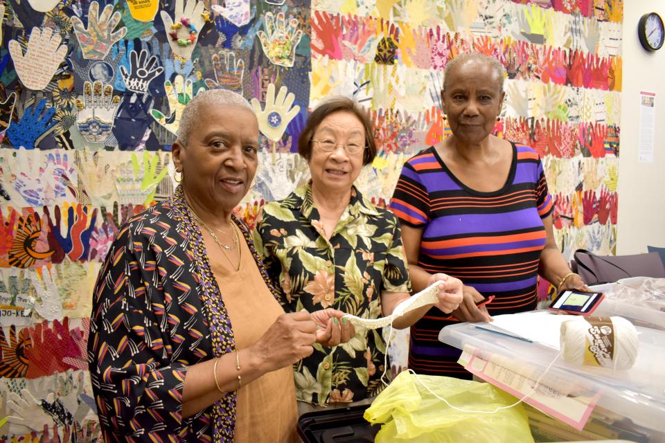 Trinity Knitters sort completed projects in the Parish Center with a background of the American flag.