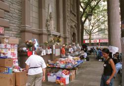 Volunteers serve hot food amidst boxes of donated food and memorial flowers