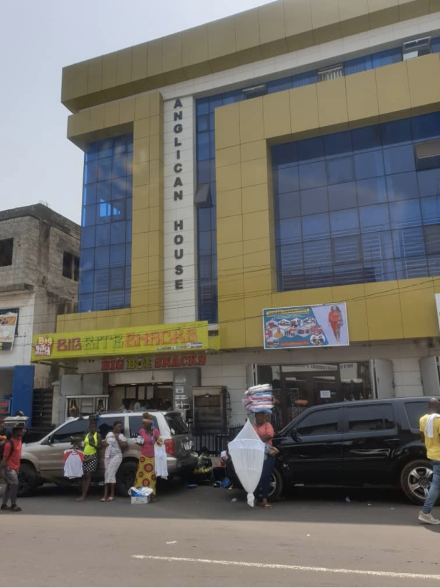 Exterior shot of the Anglican House structure in Freetown, Sierra Leone. People stand outside the building in the foreground.