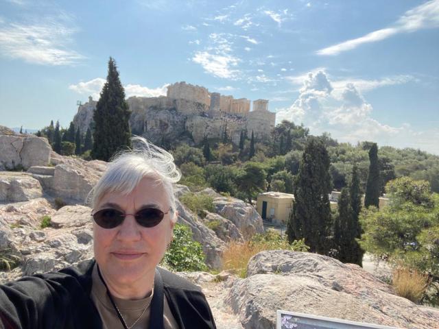 Woman stands in ancient buildings on a distant hill
