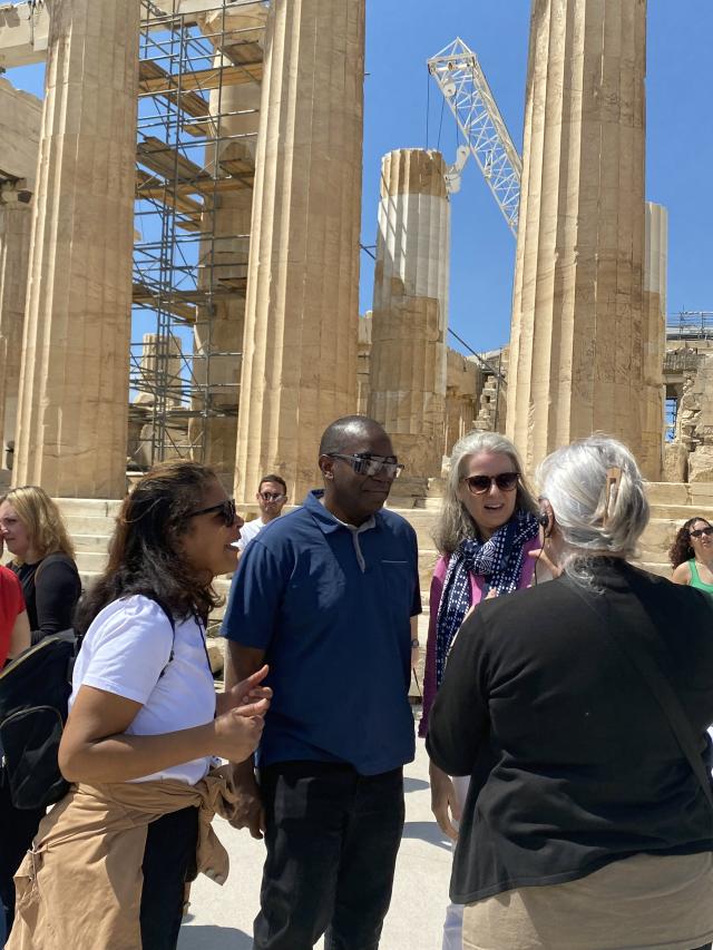 Four people stand in front of an ancient building