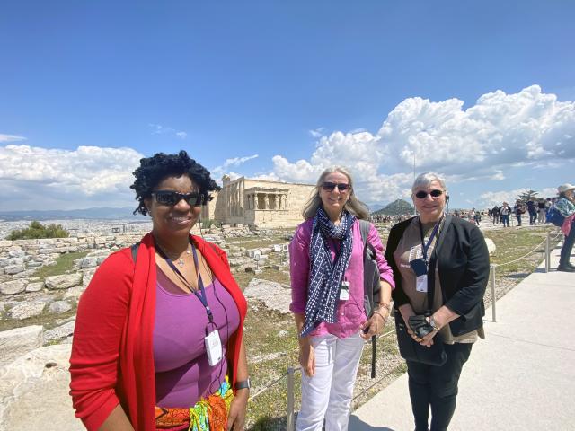Three women stand in front of an ancient building