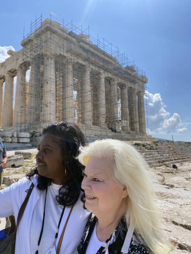 Two women stand in front of an ancient building