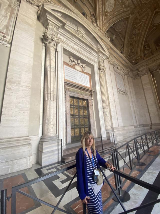 Woman stands in front of large doors outside church