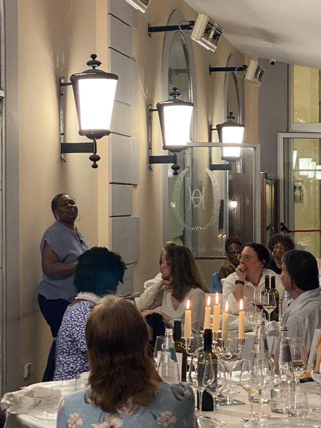 Woman stands in front of people sitting at tables