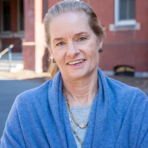 Alison Overseth wears a blue wrap over a grey tee and gold chains.