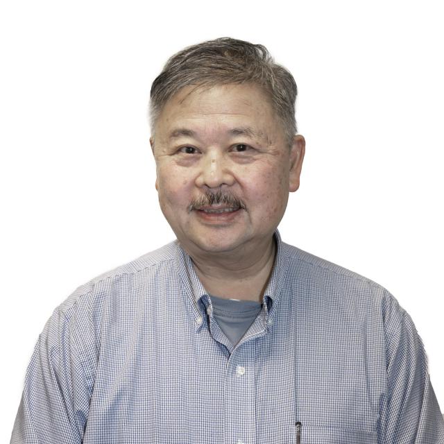 Don Hong smiles wearing a button down shirt with his collar open.