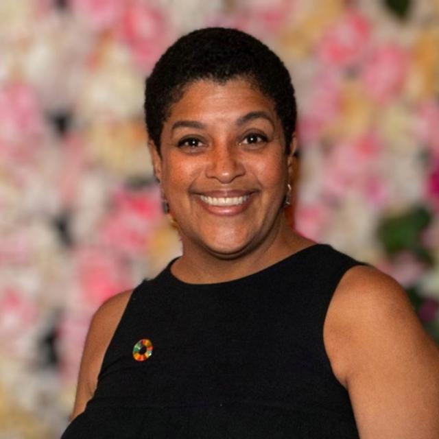 Minerva Diaz smiles wearing a black boatneck top and pin.