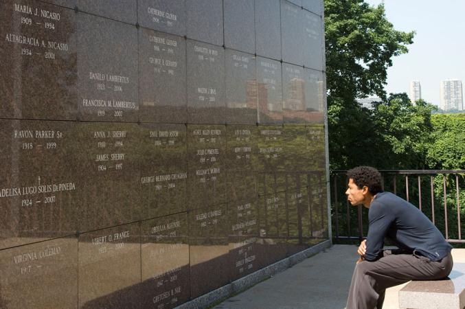 Man sits on a bench in front of one of the walls of the mausoleum