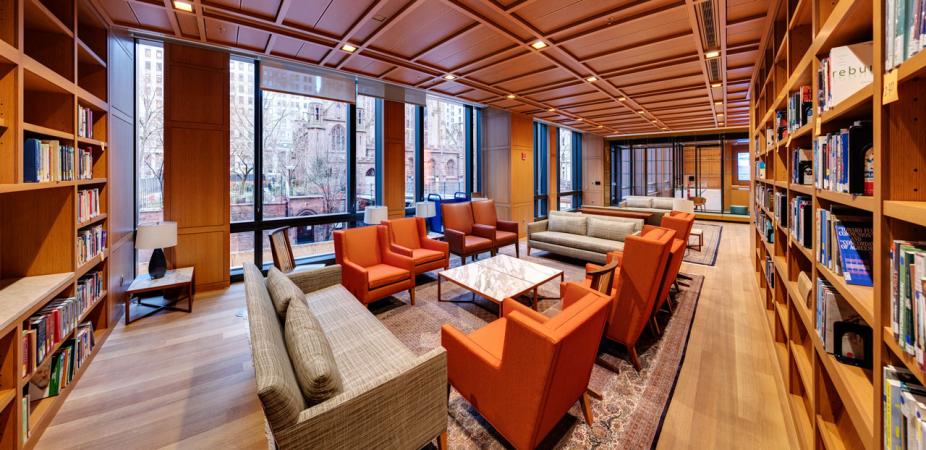 View of the library with armchairs, sofas and built-in bookshelves and a view of Trinity Church