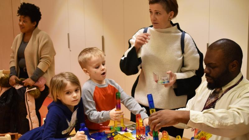 Adults and children play with colorful structures in the Gathering Spaces of Trinity Commons