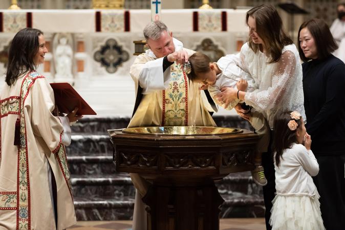 A child is baptized in Trinity Church on All Saints Sunday 2021