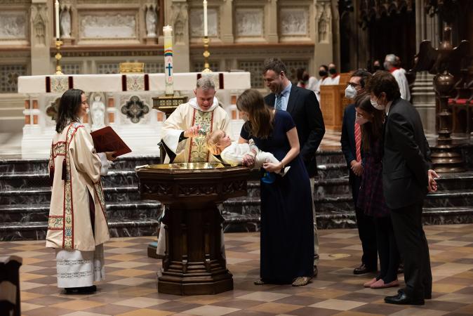 A child is baptized in Trinity Church on All Saints Sunday 2021