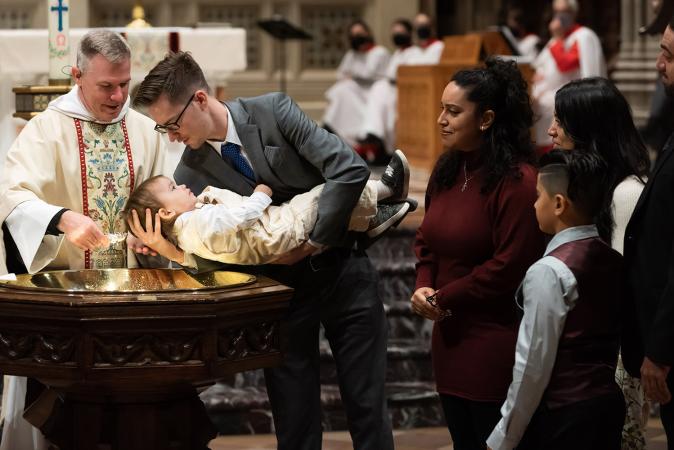 A child is baptized in Trinity Church on All Saints Sunday 2021