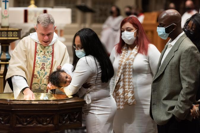 A child is baptized in Trinity Church on All Saints Sunday 2021