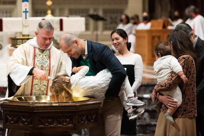 A child is baptized in Trinity Church on All Saints Sunday 2021