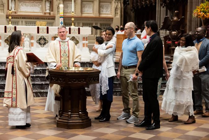 A child is baptized in Trinity Church on All Saints Sunday 2021