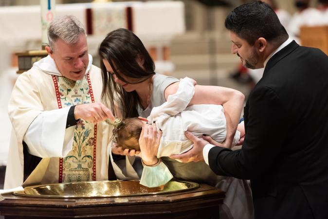 A child is baptized in Trinity Church on All Saints Sunday 2021