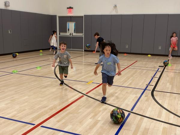 Two boys playing soccer in the Trinity Commons gymnasium 