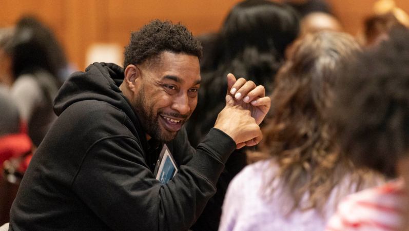 Man sitting at a table smiles at his conversation partner