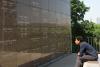 Man sits on a bench in front of one of the walls of the mausoleum