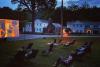 Socially-distant movie night. Film projected onto a screen and chairs arranged in the grass as night falls