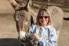 Guest holds and chicken while a donkey nuzzles her arm