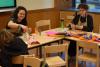 Three young women work colorful pipe cleaners and pom poms into fanciful sculptures during an art workshop.