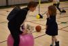 Adults and children play with an exercise ball on the basketball court.