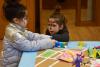 Two girls with fancifully-painted faces play at a low table.