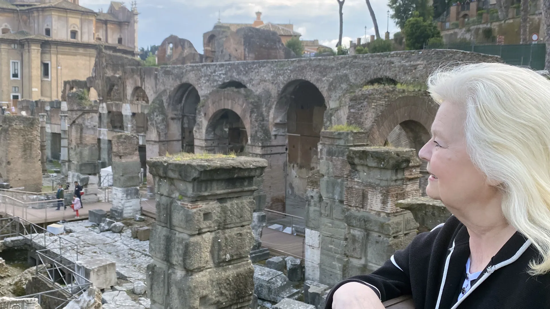 Woman stands at railing looking out over ancient city