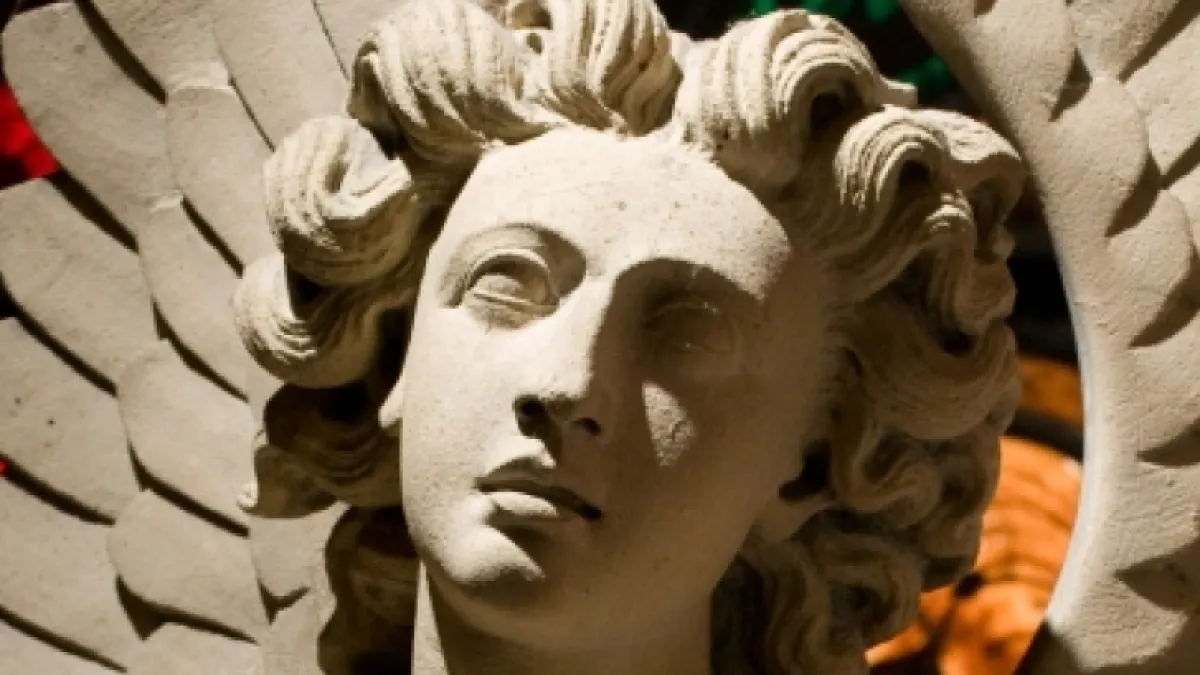 Stone angel statue and stained glass in background