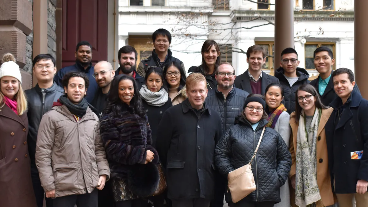 A group of young adults smiles on the steps of St. Paul's Chapel
