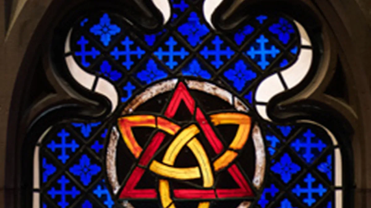 A stained glass window featuring a gold trinity knot inside a red triangle over a blue backdrop