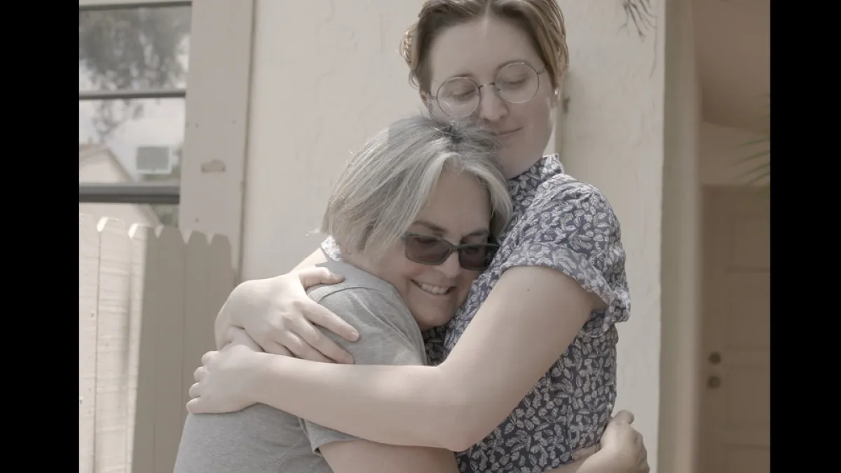 Women hugging in front of a home; Pride Family Shorts
