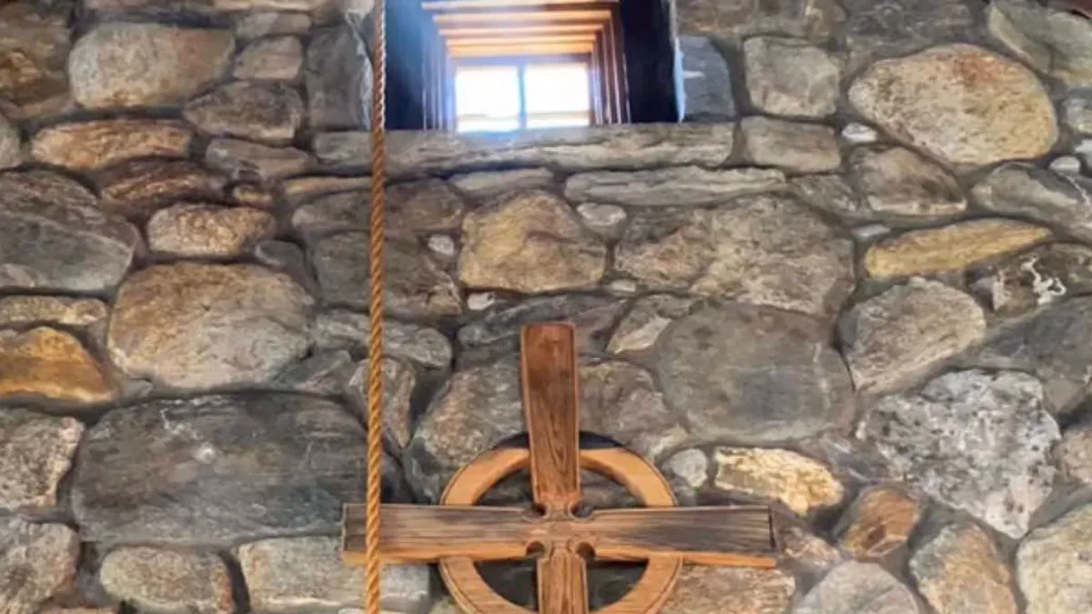 Beam of light coming in through a small window in a stone wall of the Retreat Center chapel, above a wooden cross