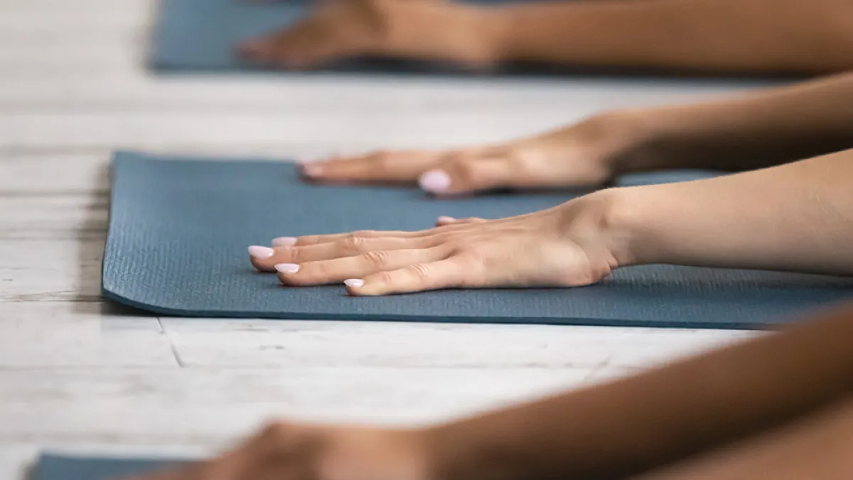 Yoga hands outstretched on green mats