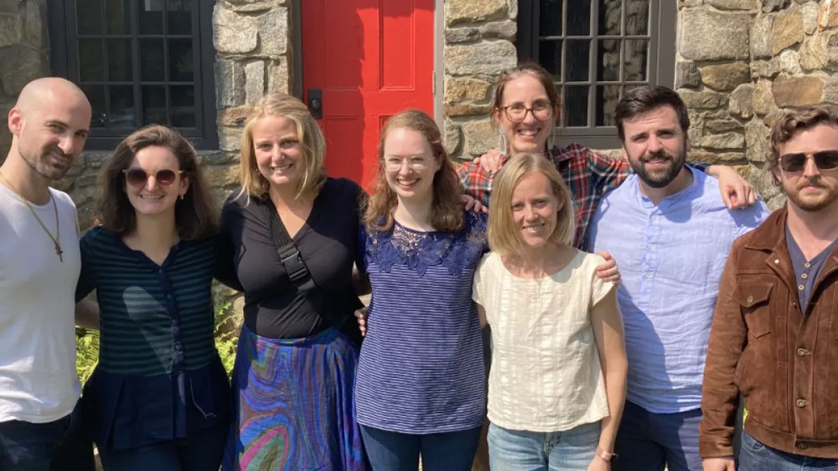 A group of young adults gathers in front of the stone chapel at Trinity Retreat Center